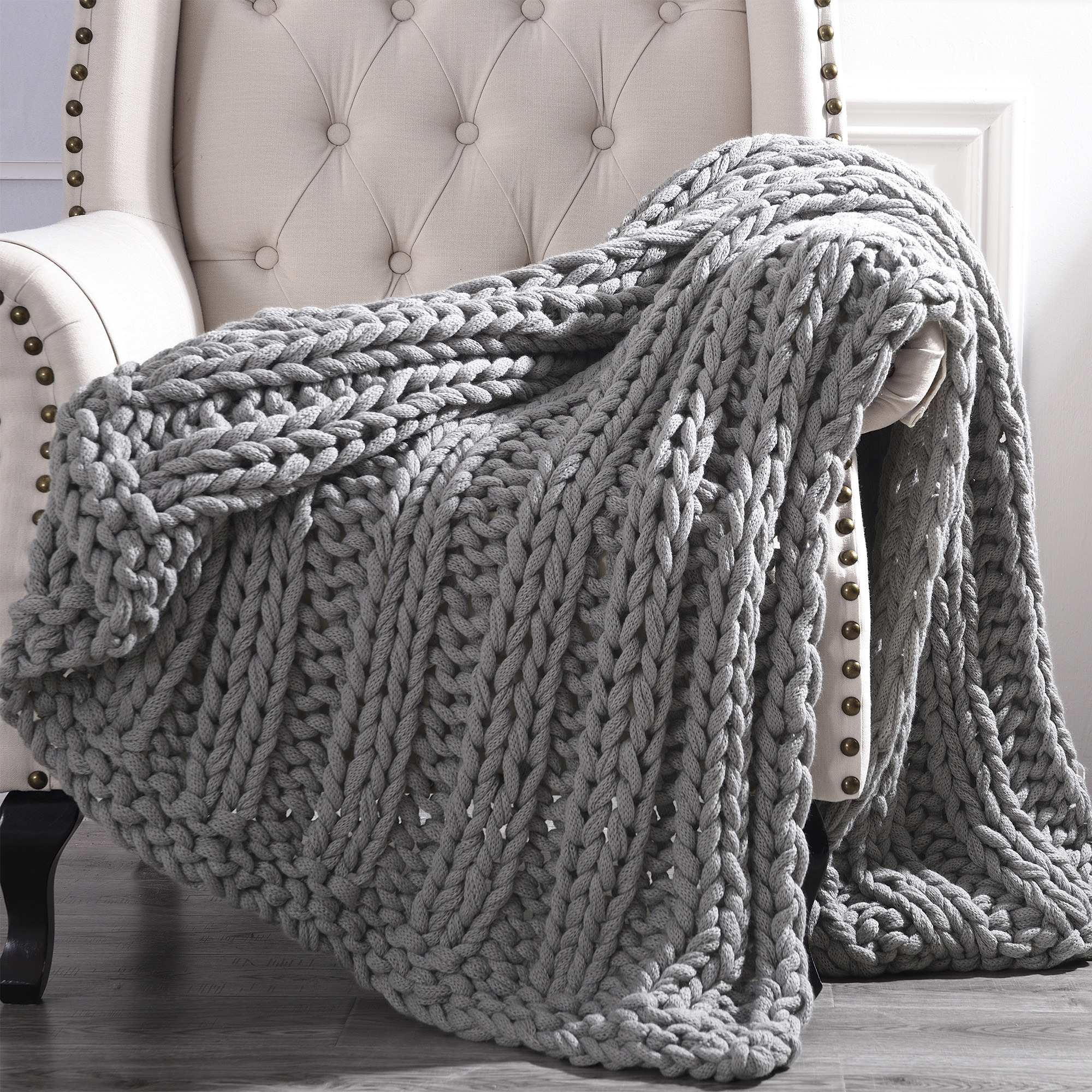 Chunky gray knitted blanket draped over a chair.