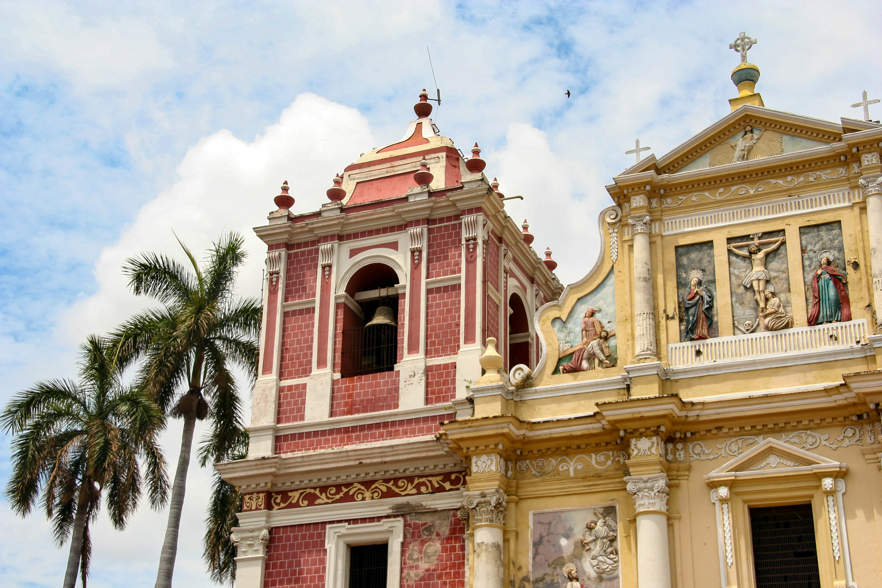 Colorful church buildings with religious art on the facade, next to two palm trees