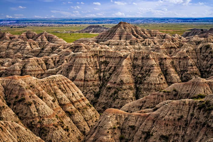 Lined rock formations leading to green plains