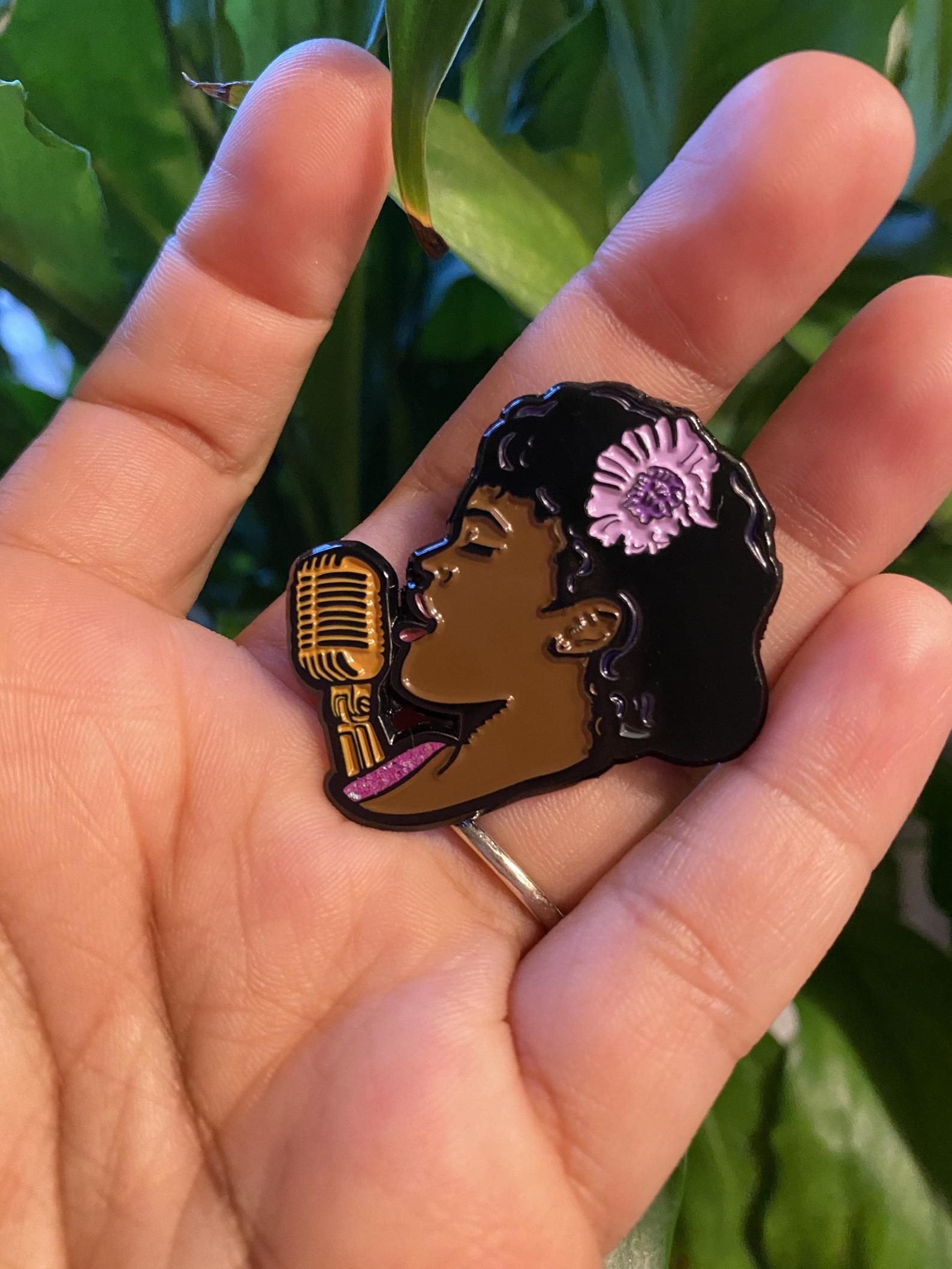 someone holding an enamel pin of the Lovecraft Country character Ruby Baptiste