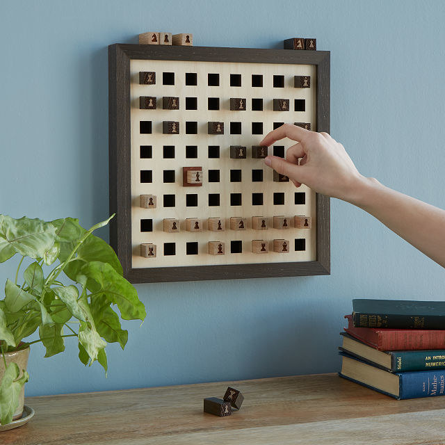 Person is moving a chess piece on a wall-mounted chess board
