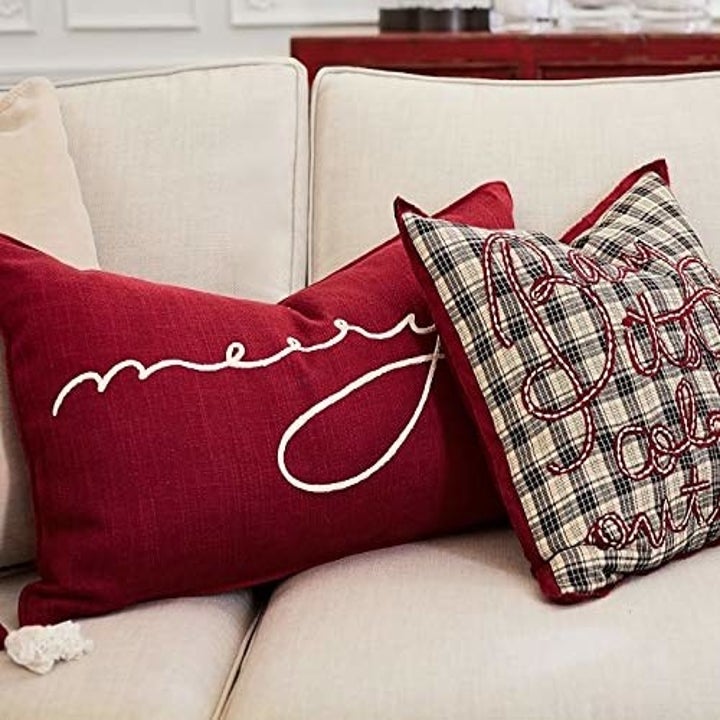 A maroon throw pillow with the word 'merry' on it.