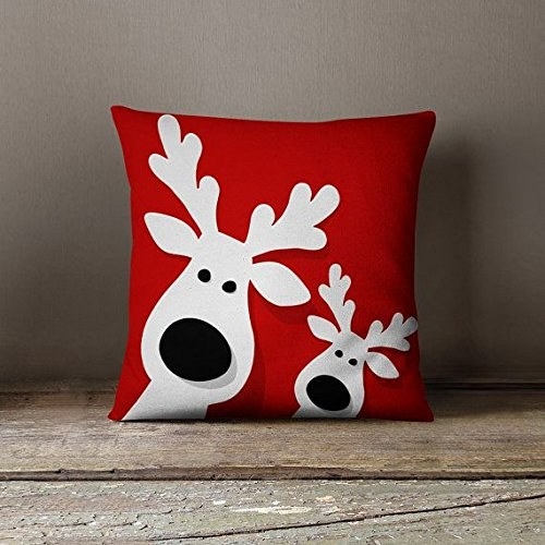 A bright red cushion with two white reindeers on it.