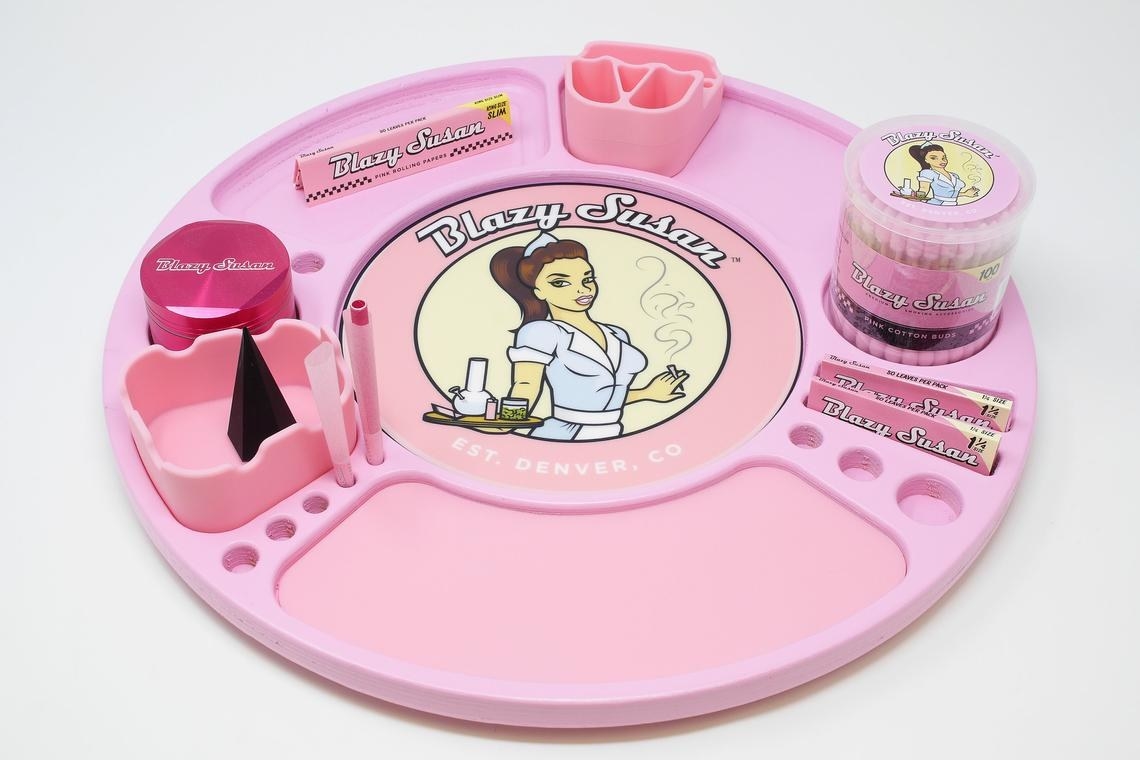 A pink lazy susan-shaped product with papers, a dab mat, and ashtray