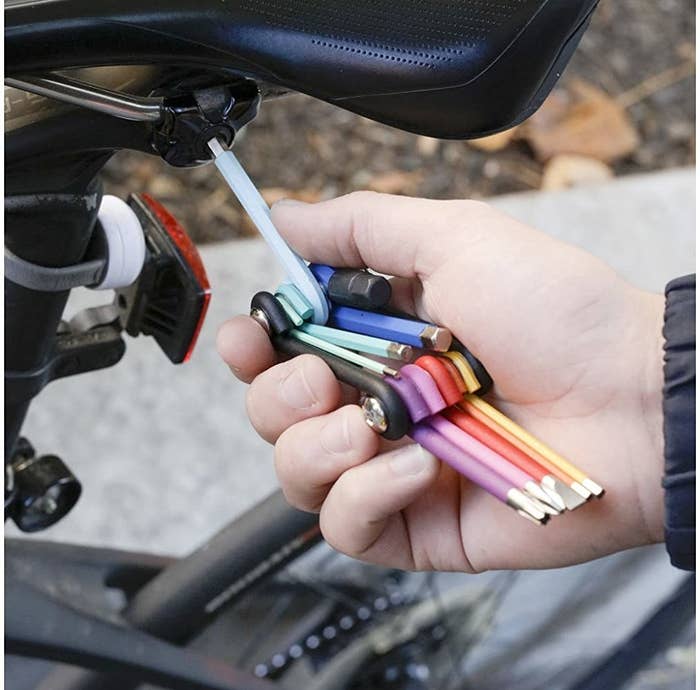 A person uses one of the allen keys on the multi-tool to fix their bike seat