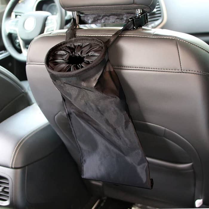 Collapsable fabric trash bin with handles wrapped around passenger seat and sealed top 