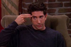Ross Geller holding two fingers to his temple