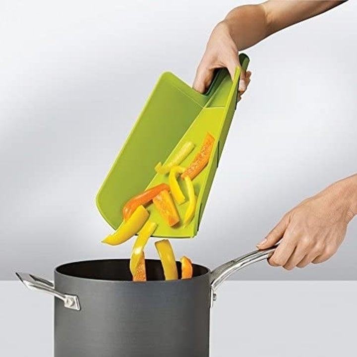 model transferring cut peppers into pot with green cutting board