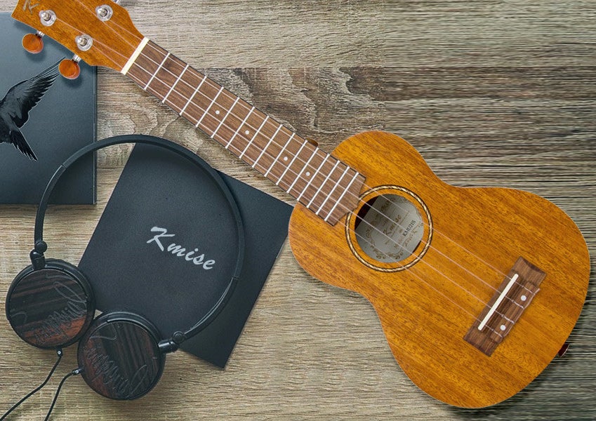 A ukulele beside a pair of headphones 
