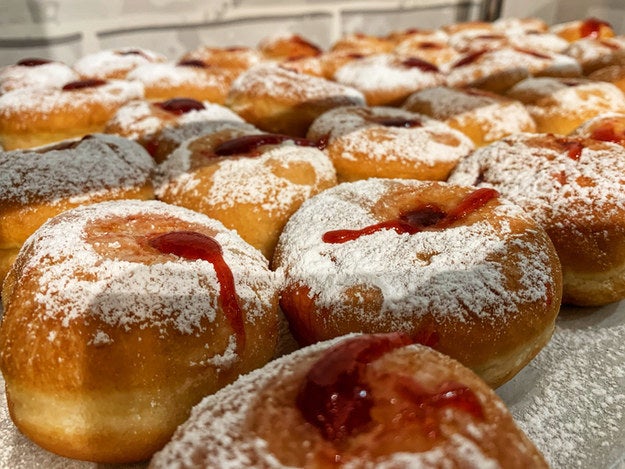 A tableful of donuts with jelly filling and powdered sugar on top