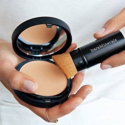 a hand holding the brush to powder foundation