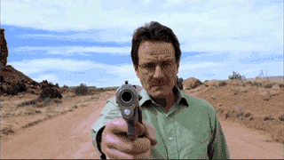 standing on a desert road, Walt aims a gun as the camera zooms in on it