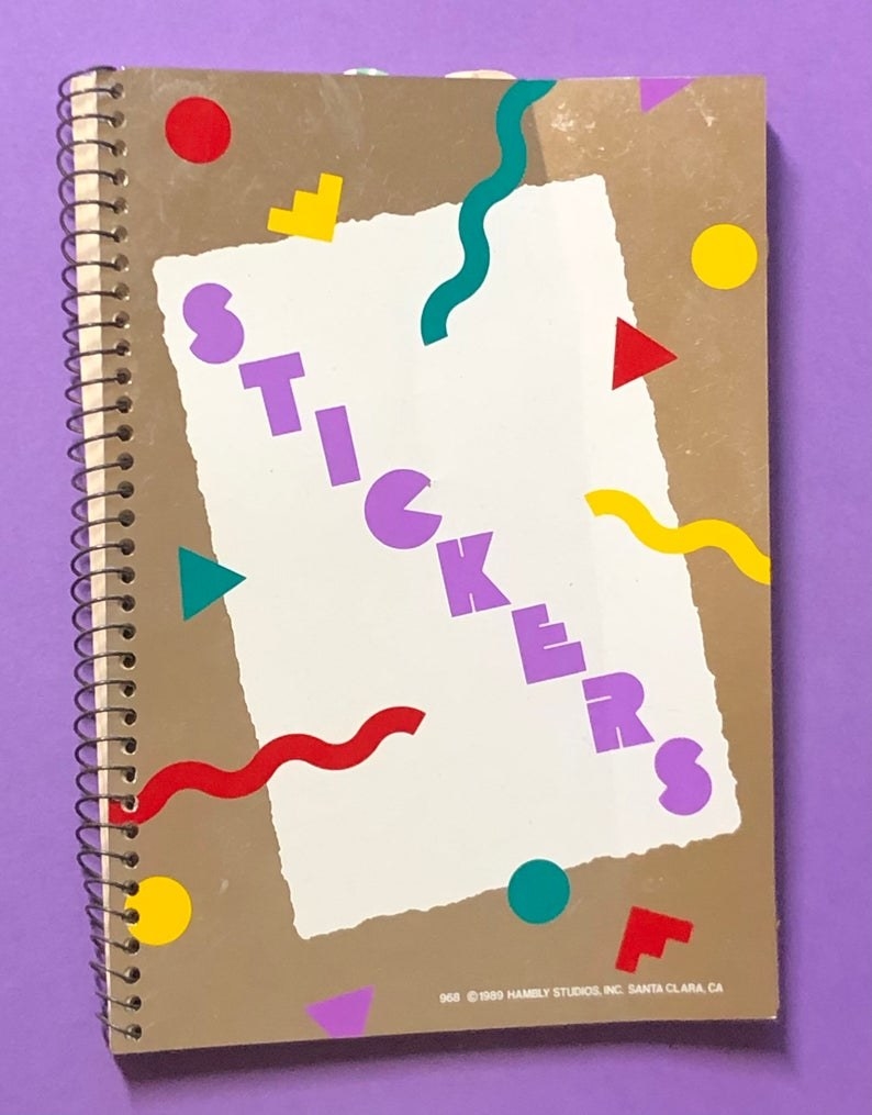 A spiral-bound sticker book with &quot;stickers&quot; in purple letters written in the front of them