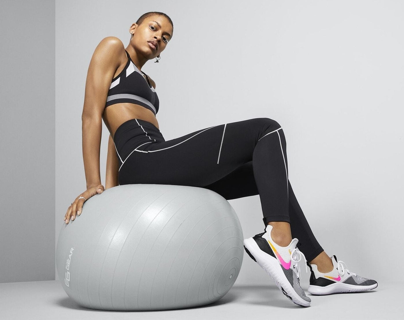 Model wears pink, orange, and black Nike Free TR8&#x27;s while stabilizing core on a ball