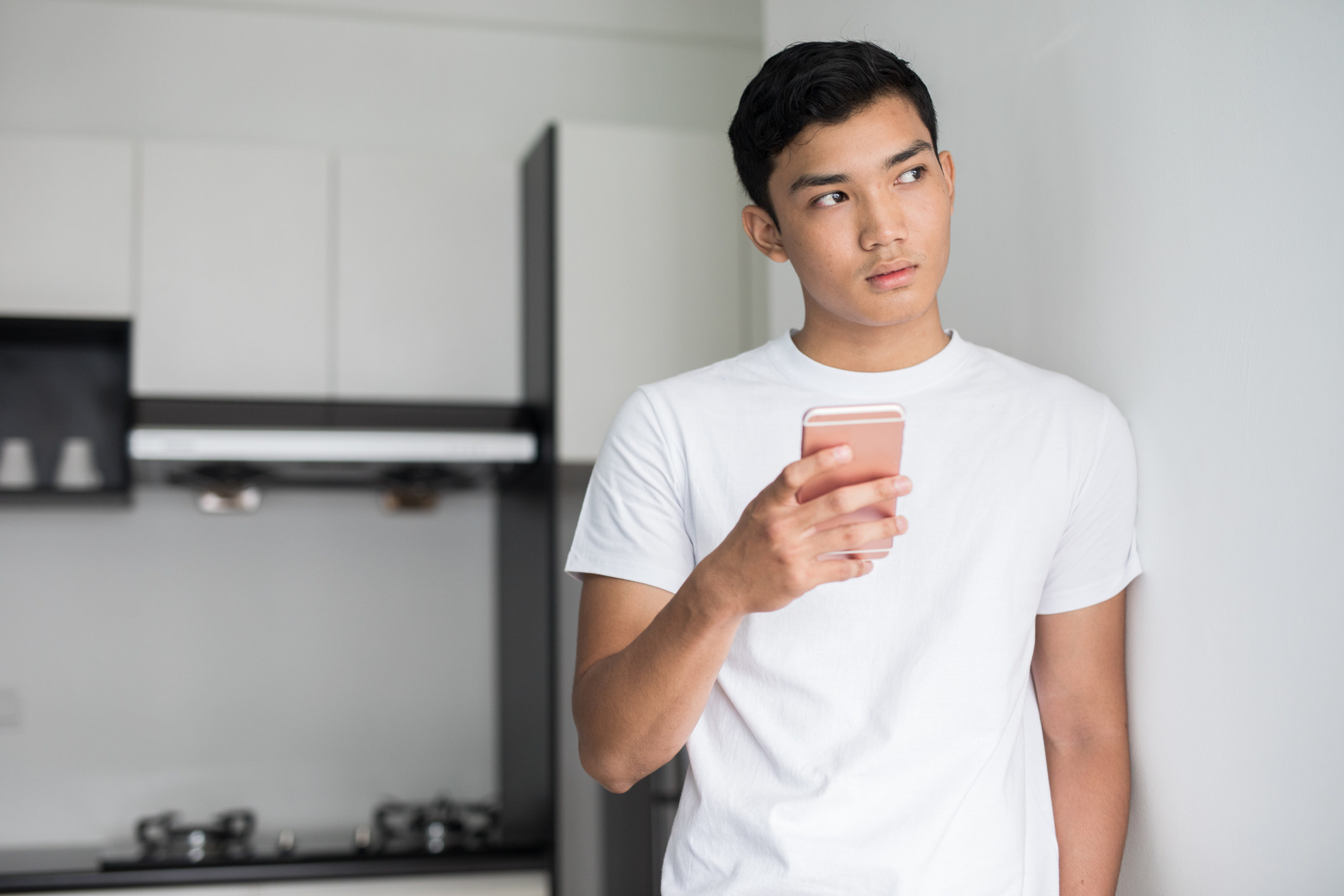 photo of a man holding up a phone and thinking