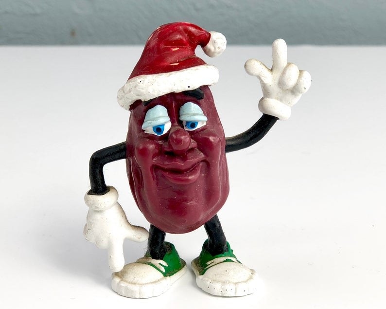 A California Raisin figure with its hand up and a Santa hat on