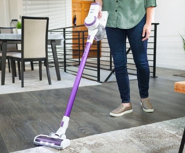 person using a purple tineco cordless vacuum