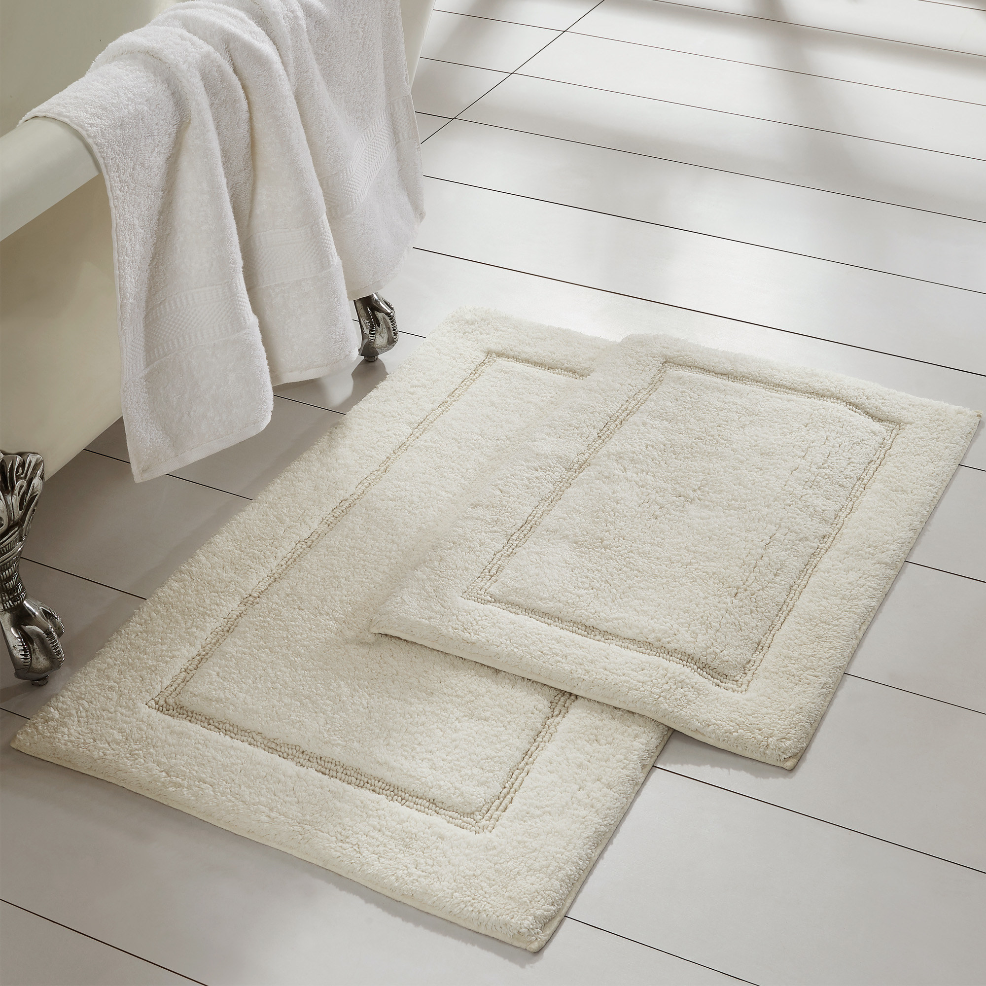 a big and small rug in the color ivory laid out on a bathroom floor
