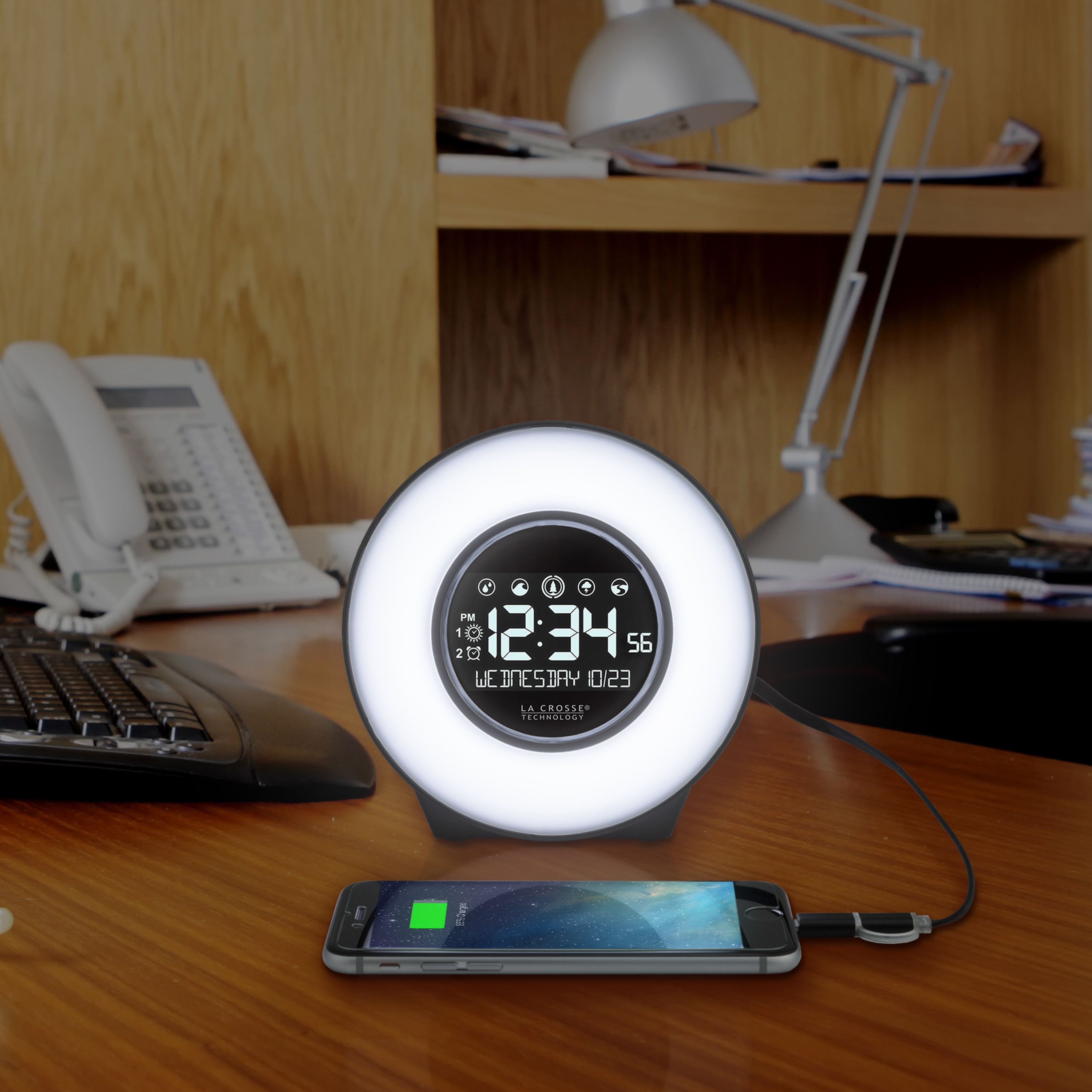 desk clock with white light glowing and a phone charging