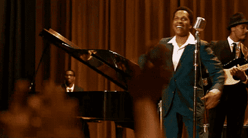 Leslie wearing a suit twirls on stage in front of a microphone as Sam Cooke in &quot;One Night in Miami&quot;