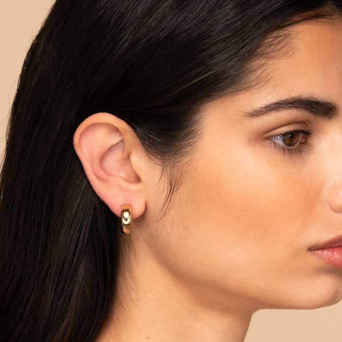 a model wearing gold dome hoop earrings