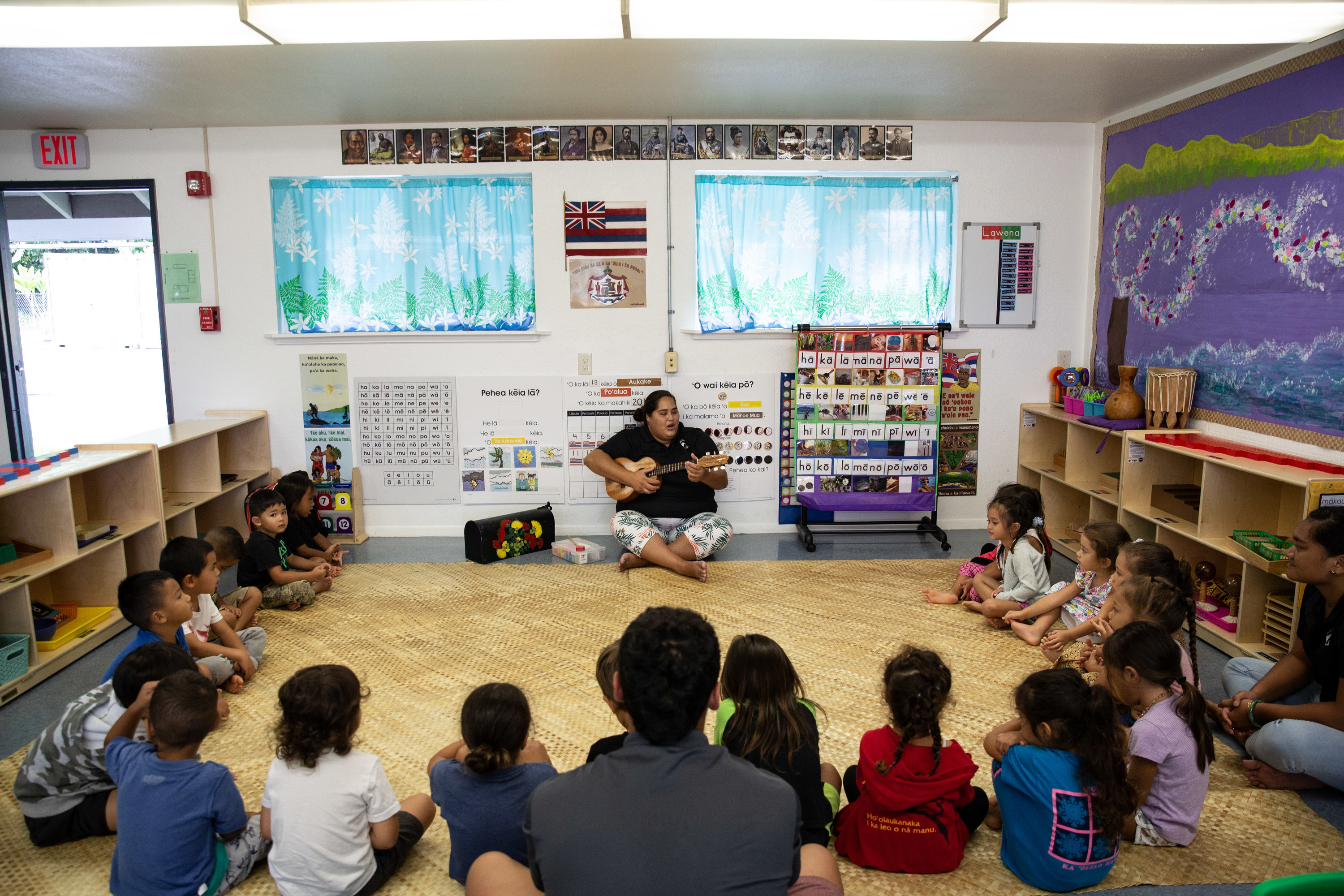 Woman with ukulele sitting in a semi circle of young children