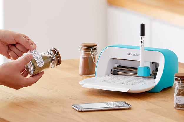 person putting a label made from a cricut machine onto a jar