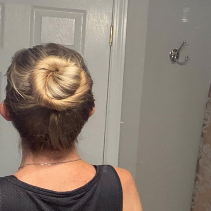 A reviewer using the hairpin to create a perfect bun