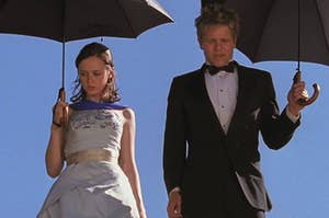 Rory and Logan from Gilmore Girls standing next to each other in formal wear holding umbrellas 