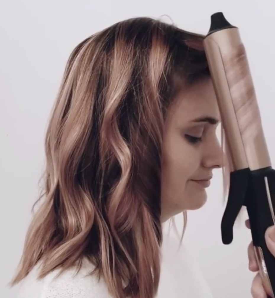 A person curling hair with a curling iron