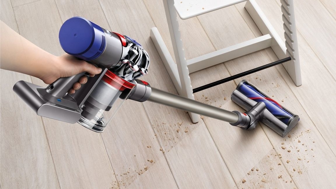 a model vacuums a dirty floor with the dyson v8 animal