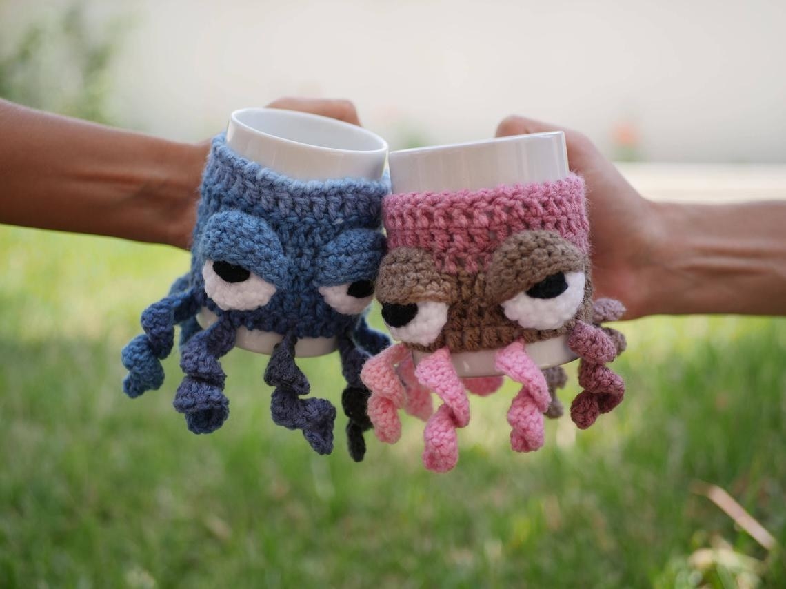 Two people holding mugs with octopus sleeves on them