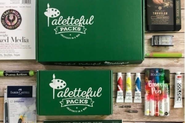 The exterior of the Paletteful Packs boxes along with supplies like paint  and a mixed media book