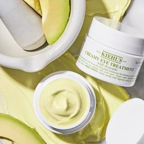 Two bottle of eye cream next to avocado in a bowl