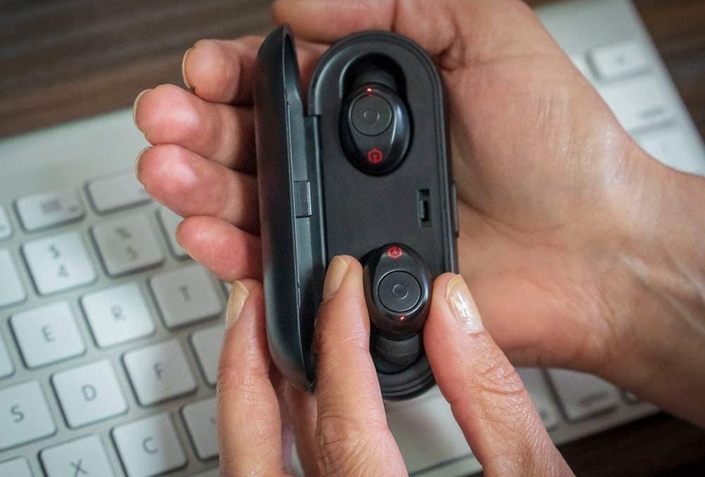 person putting one of the earphones back in the case