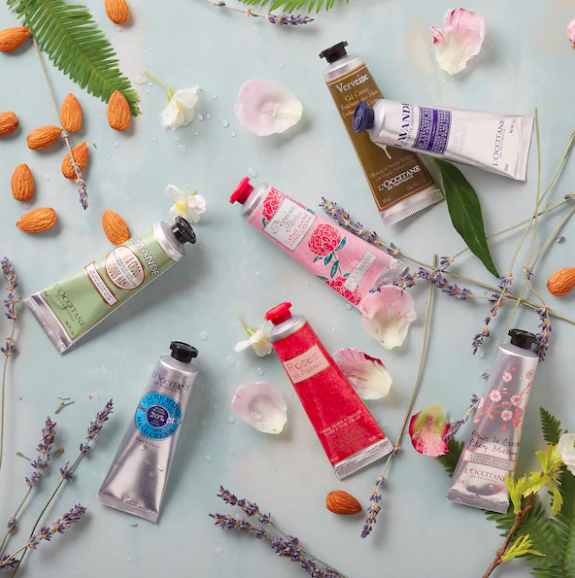 Seven tubes of different hand creams scattered on a surface with sprigs of lavender and other foliage