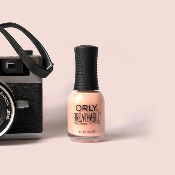 Peach nail polish next to vintage black camera