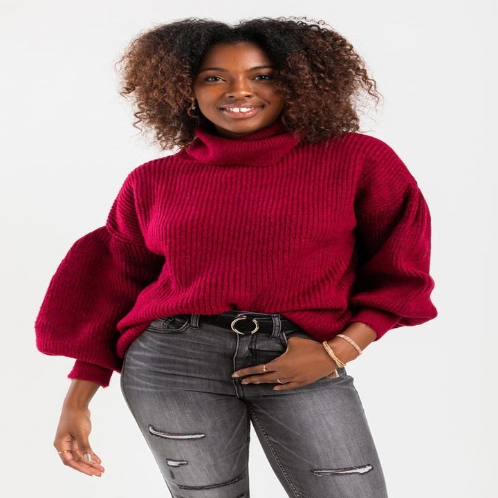 Model wears red bell sleeve-sweater with distressed jeans