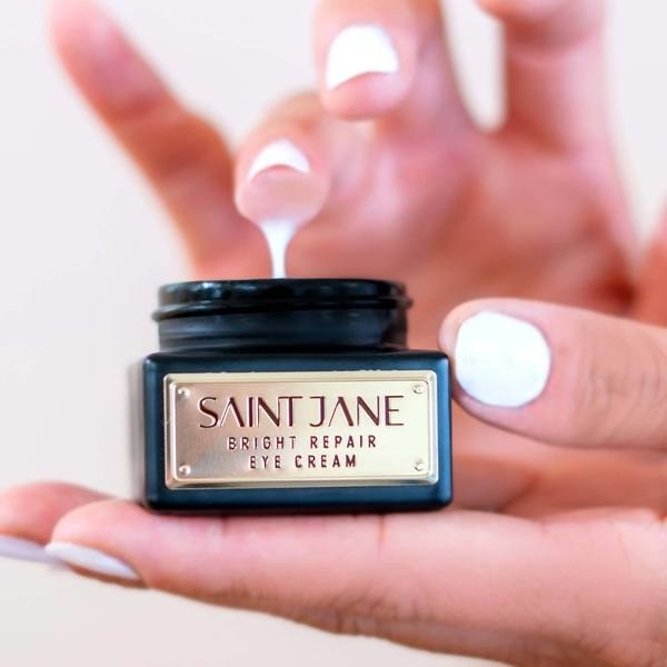 A hand dipping a finger into the Saint Jane Bright Repair Eye Cream 