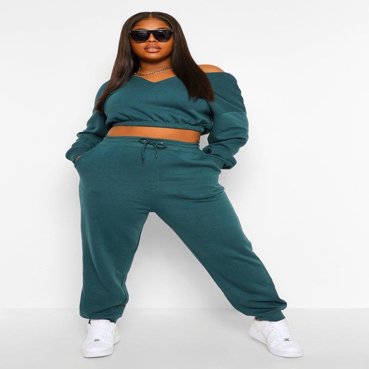 Model wears matching green v-neck cropped hoodie and joggers set with white sneakers
