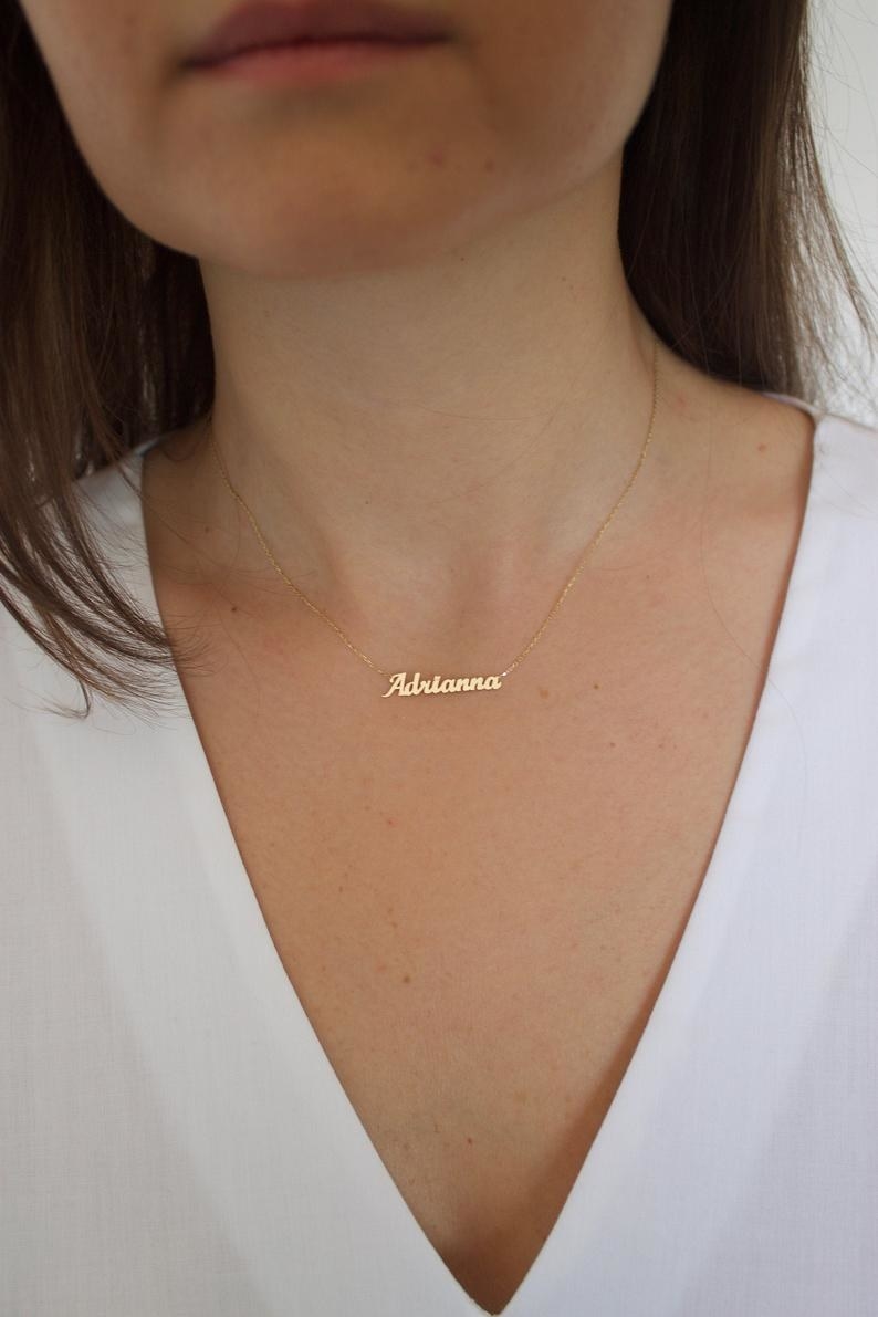 a model wearing a gold nameplate necklace that reads Adrianna in cursive