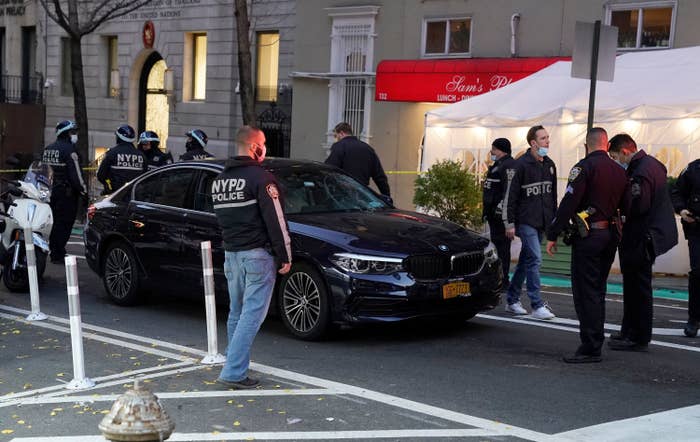 Police officers surround a black BMW in a street