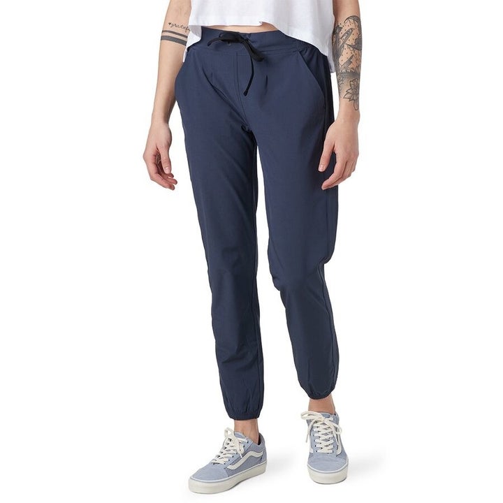 Model wears navy blue soft pants with light blue Vans