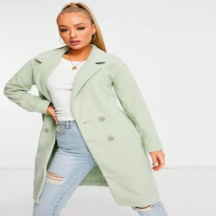 Model wears sage coat with distressed jeans and a white tee