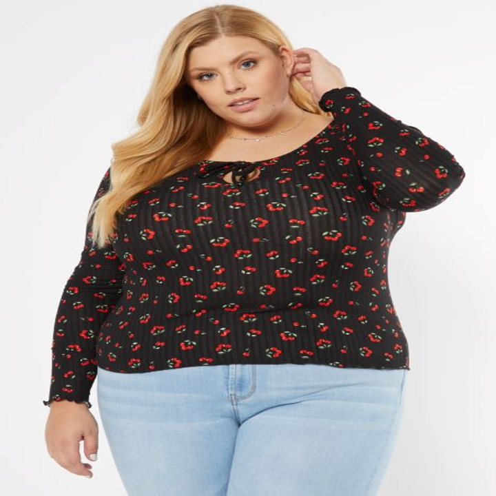 model wearing black long-sleeve top with tie detail and red and green floral print