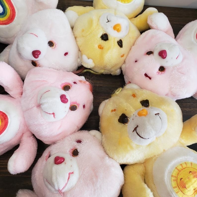 Six Care Bear stuffed animals laying on their backs with their heads forming a sort of circle 