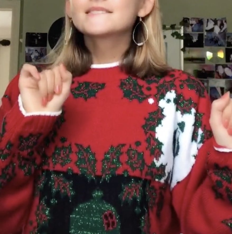 A woman in a red sweater with sparkly holly on it