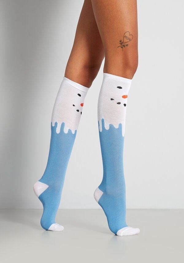 a model wearing the blue socks with a snowman face on them and white detailing 