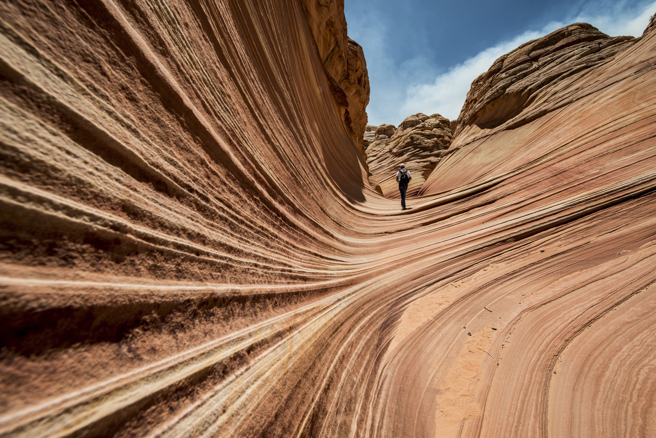 一个徒步旅行者走在一个红色的岩石看起来像波