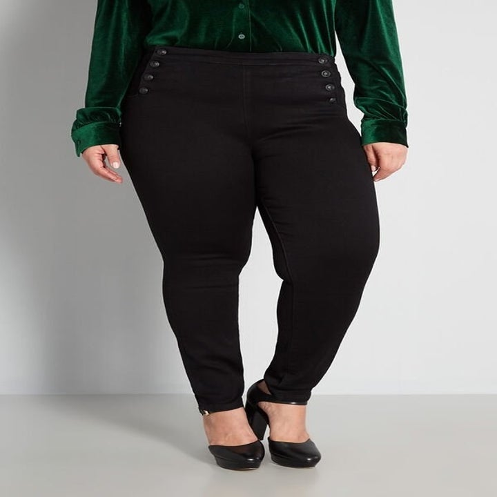 a model wearing the black sailorette jeans with decorative buttons